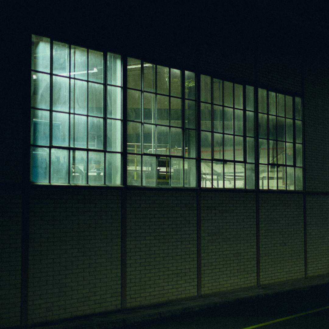 Factory windows at night. Light is coming through the windows.